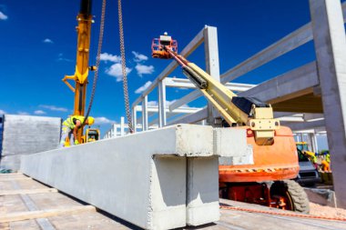 İşçi kamyon yolundaki beton kirişe vinç kancaları takıyor.