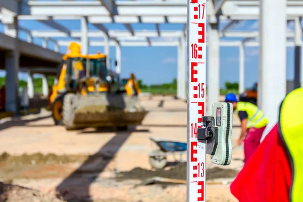 Trabajador está sosteniendo la barra de nivelación para medir el nivel en la constructio — Foto de Stock