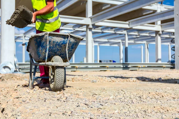 Trabajador está usando carretilla de descarga de pala en el sitio de construcción — Foto de Stock