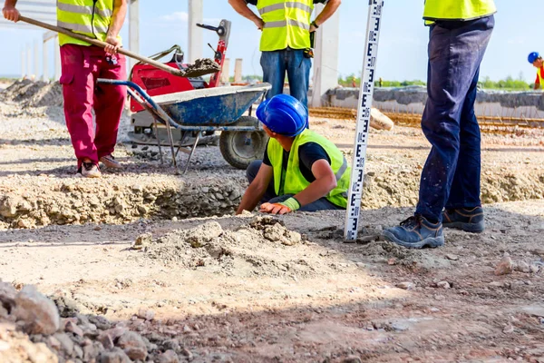 Worker is using tool to set up right measures in square trench — Stock Photo, Image