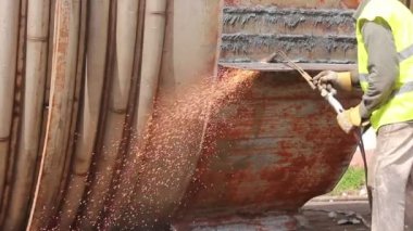 İşçi, oksijen, asetilen ve propan karışımı kullanarak elle eski metal yapısını kesiyor..
