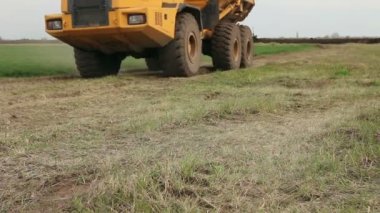 Büyük kamyon gidiyor, şantiyeden geçiyor. Şantiyede geçerken damperli kamyon alt vagonuna yakın görünüm.