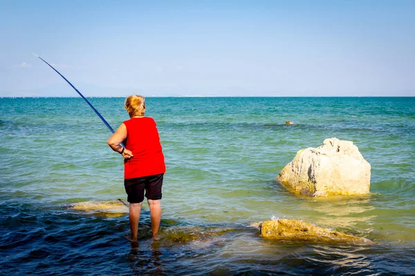 Seniorin fischt im Meer — Stockfoto