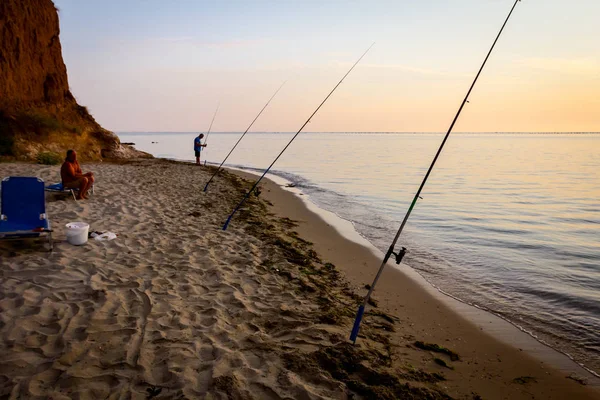 Silhouette von zwei Freunden, die in der Sonne am Strand fischen — Stockfoto