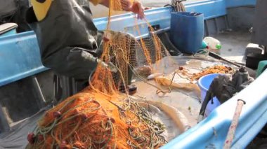 Fisher kauçuk pantolon ve çizme onun tekne de oturarak ve açık denizde olta için balıkçılık ağı kazık. Fotoğraf - Jpeg video codec