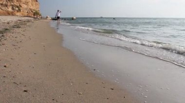 Adam yalınayak yalak sığ deniz suyu, kumlu plajda güzel yürüyüş zevk yürüyor. Fotoğraf - Jpeg video codec            