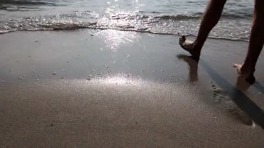 Yalınayak turist huzurlu yürüyüş, kumlu plajda dinlenme, sığ sularda yürüyüş tadını çıkarıyor. Fotoğraf - Jpeg video codec
