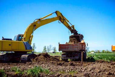 Ekskavatör bina site üzerinde zemin ile bir kamyon yükleniyor