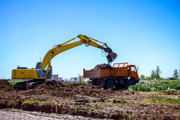 挖掘机正在建筑工地上装载一辆有地面的卡车 — 图库照片