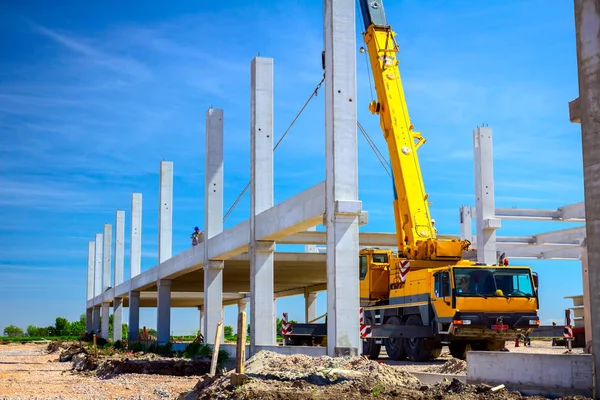 Żuraw samojezdny niesie betonową belkę do montażu ogromnej hali — Zdjęcie stockowe