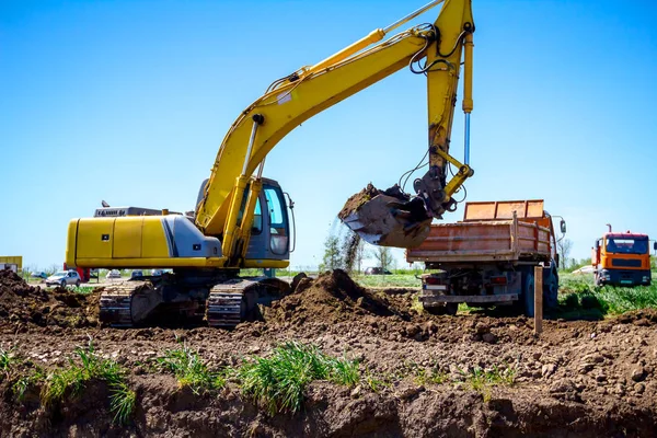 Ekskavatör bina site üzerinde zemin ile bir kamyon yükleniyor