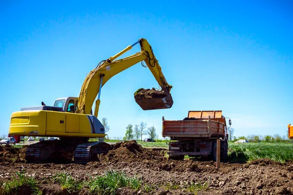 Ekskavatör bina site üzerinde zemin ile bir kamyon yükleniyor