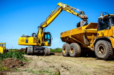 Ekskavatör bina site üzerinde zemin ile bir kamyon yükleniyor