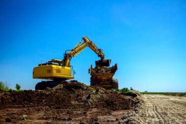 Ekskavatör bina site üzerinde zemin ile bir kamyon yükleniyor