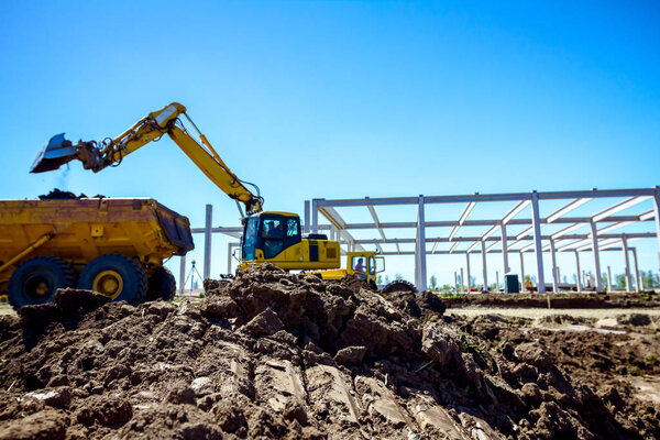 Backhoe is loading a truck with ground on building site