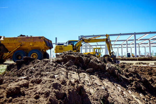 Backhoe is loading a truck with ground on building site