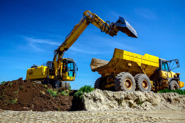 Excavator is loading a truck with ground on building site
