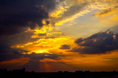 Gün batımında kümülüs bulutları ile karanlık gökyüzü altında şehrin silueti 