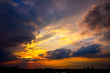Gün batımında kümülüs bulutları ile karanlık gökyüzü altında şehrin silueti 