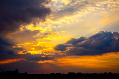 Gün batımında kümülüs bulutları ile karanlık gökyüzü altında şehrin silueti 