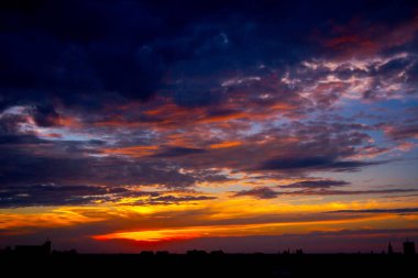 Gün batımında beyaz bulutlarla mavi gökyüzü, uzaktaki kasaba 
