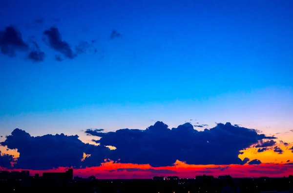 Céu azul com nuvens brancas ao pôr do sol, cidade à distância — Fotografia de Stock