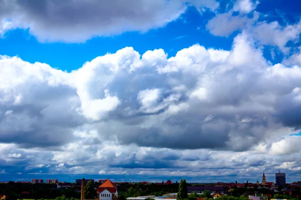 Γαλάζιος ουρανός με λευκά σύννεφα, πόλη σε απόσταση — Φωτογραφία Αρχείου