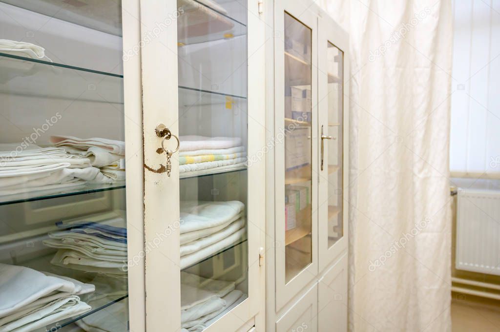 Obsolete medical cabinet with clean tidy bed sheets and towels
