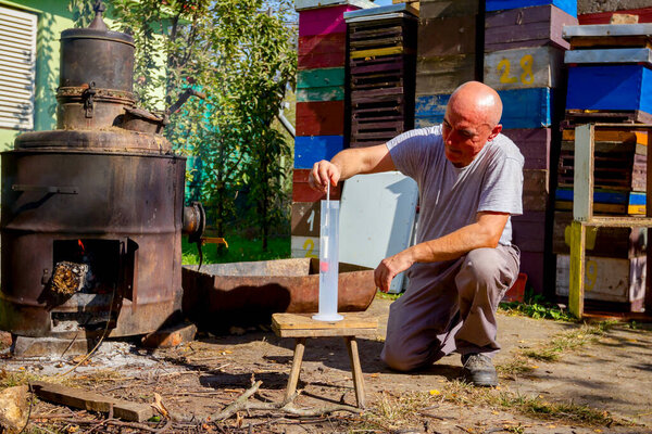 Человек использует стеклянный спирт для определения количества, концентрации алкоголя в спирте. Образец помещается в цилиндр лабораторного выпуска.
