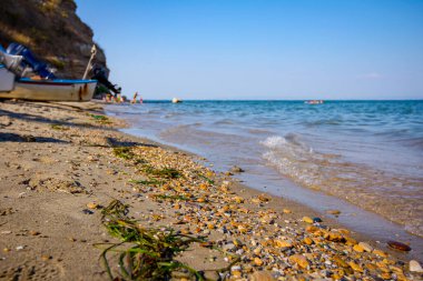 Çakıl taşlı kıyı şeridindeki küçük dalgaların alçak açılı görüntüsü, köpüklü dalgalarla dolu deniz.. 