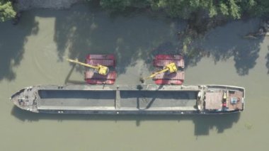 Kazı aracının hava görüntüsü tarıyor, nehir, kanal, tortu derinleştiriyor ve kirli bir su yolundaki çamur kaldırıyor. 4K Merkez 30fps DLog-M H.265 10 Bit Rengi