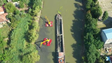 Kazı aracının hava görüntüsü tarıyor, nehir, kanal, tortuyu derinleştiriyor ve kirli bir su yolundaki çamurdan temizliyor..