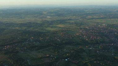 Dolly yeşil tepe üzerinde çekim yaptı, uzaktaki orman ağaçları ve şehir arasında ekilmiş araziler. Kırlangıçlar uçuşuyor.