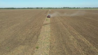 Traktör, ekilebilir alanı yıpratan ve toprağı gelecek sezon için hazırlayan bir disk dişli makineyi çekiyor. Aç kuş sürüsü, beyaz martılar yiyecek aramak için tarımsal makineyi takip ediyor..