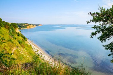 Çimenlerle ve ağaçlarla kaplanmış uçurum deniz kıyısının üzerindedir. Uzakta yerleşim 
