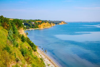 Çimenlerle ve ağaçlarla kaplanmış uçurum deniz kıyısının üzerindedir. Uzakta yerleşim 