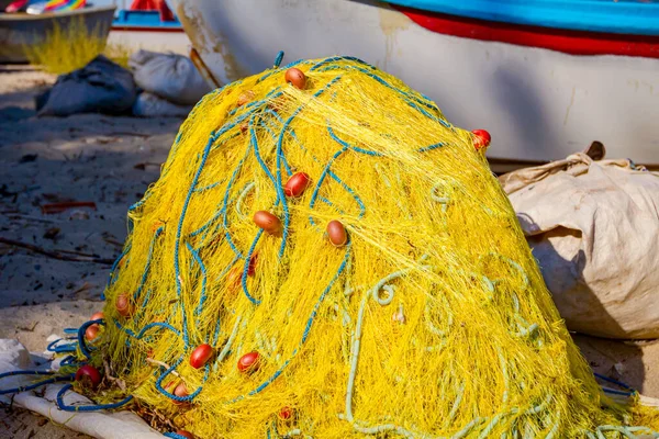 Pile of commercial fishing net on the sandy beach, equipment for angling at open sea.