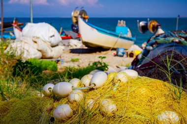 Ticari balık ağı yığını kumlu plaja yerleştirilir, balıkçı tekneleri kuru kenetlenir.. 
