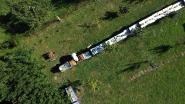 Yukarıdan bakıldığında, arı yetiştiricisi çizgi halinde, ahşap renkli arı kovanlarında, sıra sıra dizilmiş arı kolonilerinde durumu kontrol ediyor.. 