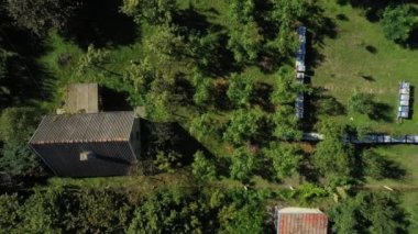 Tepeden aşağıya doğru yavaşça taşıyın, arı yetiştiricisi çizgi halinde sıralanmış ahşap renkli arı kovanlarındaki durumu kontrol ediyor.. 