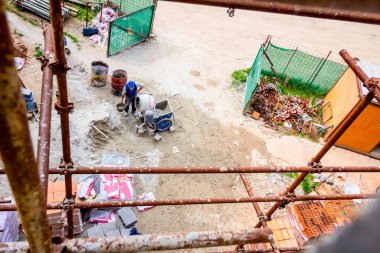 İnşaat çalışanları inşaat alanının üstünde mikserde beton yapıyorlar..