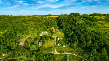Orman manzarası, dağ manzarası kır evi yerleşimi, birkaç ekili, ekilebilir arazi, kirli yollar orman ağaçlarının arasına gider..