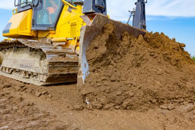 Close up view on bulldozer's undercarriage during pushing sand at construction site.	