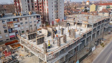 Kule vinci üzerinde koni tankı, beton karışımını taşımak ve taşımak için konik metal kova, inşaat sahasının üzerine dökülmek için, yeni tamamlanmamış çok katlı bina.