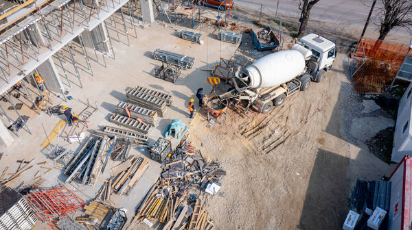 Вид сверху на процесс перевалки свежего бетона из смесителя грузовика над рампой, канал в конусном резервуаре, коническое металлическое ведро для транспортировки, доставка смеси высокой строительной площадки, повесить на крючок крана.