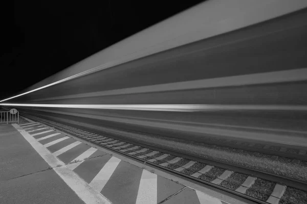 Long exposure of passing trains in the night in a train station