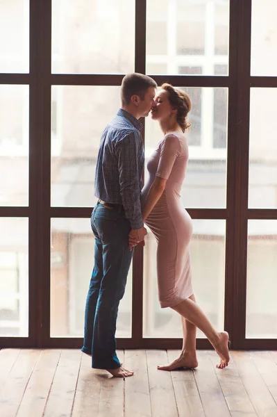 Güzel bir hamile kadın ve yakışıklı kocası karın sarılma kırpılmış görüntü 