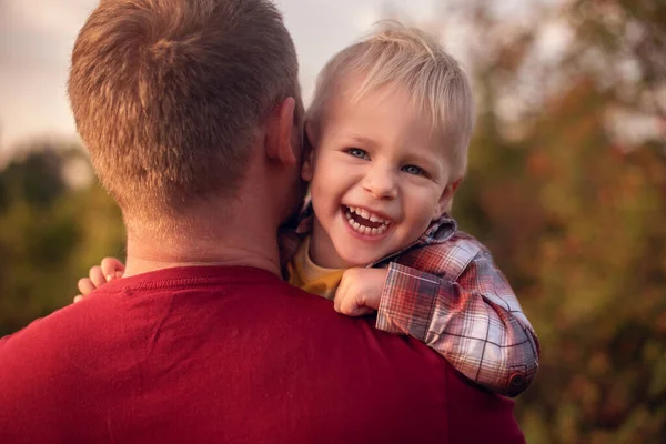Baba küçük oğlunu dışarıda sırtında taşıyor.