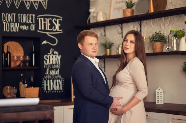 Yakışıklı adam güzel hamile karısının karnını dinliyor ve gülümsüyor.