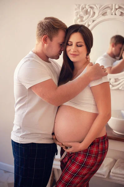 英俊的男人正在听他美丽的怀孕妻子的肚子 微笑着 — 图库照片